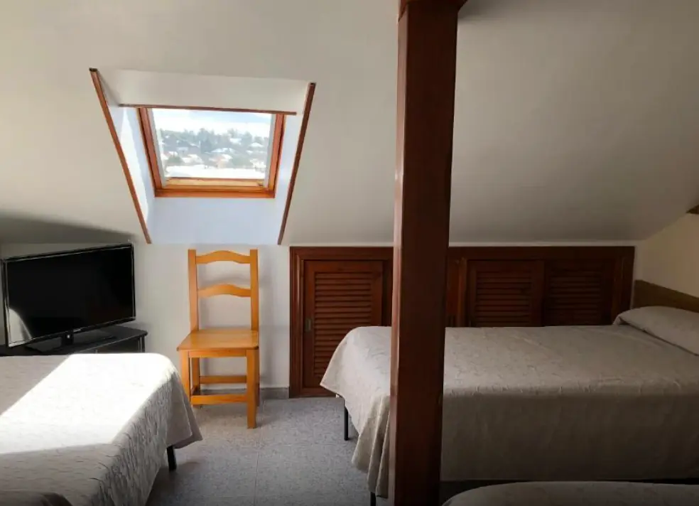 Habitación triple con televisión y ventana al pueblo